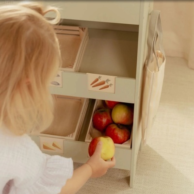 Móvel infantil com maçãs e gavetas de madeira com etiquetas ilustradas.