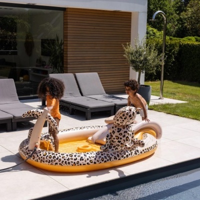 Piscina insuflável para crianças com padrão de leopardo ao lado de piscina maior com crianças a brincar