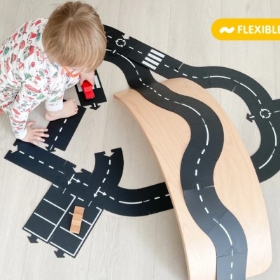 Criança a brincar com tapete flexível para estrada e brinquedos no chão