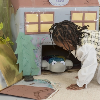 Casa de brincar em cartão com criança a observar brinquedo no chão