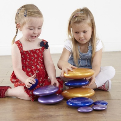 Duas raparigas sentadas no chão a brincar com discos coloridos de plástico