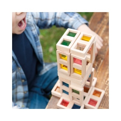 Blocos de madeira coloridos empilhados sobre mesa com criança ao lado