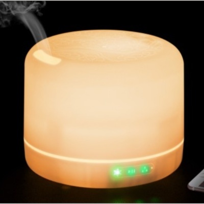 Difusor de aroma elétrico redondo bege com luz amarela e indicadores verdes, emitindo vapor