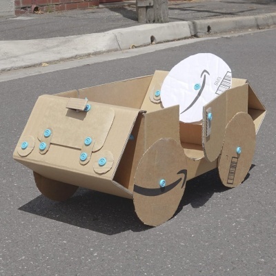 Carro de papelão com parafusos azuis e logo Amazon nas rodas