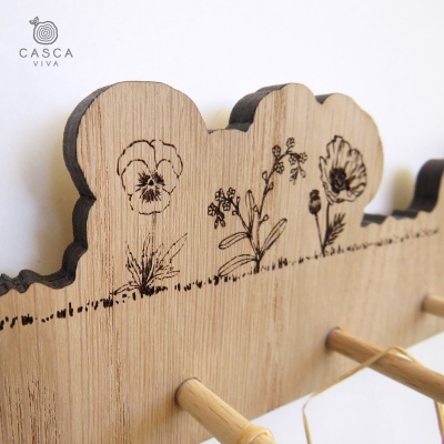 Cabideiro de parede em madeira clara com flores gravadas e varões