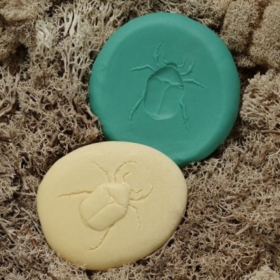 Sabonetes verde e creme com gravação de inseto sobre musgo seco