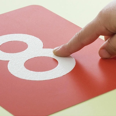 Etiqueta vermelha com número 8 branco em relevo tocado por dedo