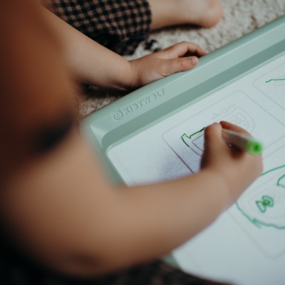 Criança a desenhar numa mesa de desenho com caneta de água e bordas verdes