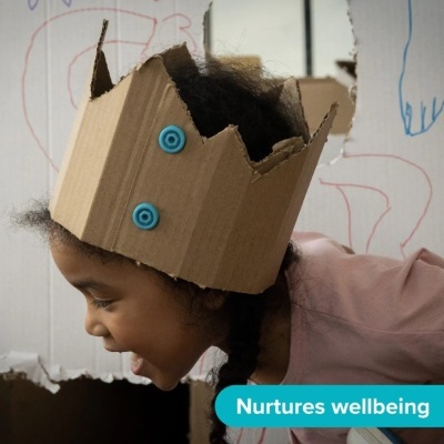 Criança com coroa de cartão castanho e botões azuis em fundo com desenhos coloridos