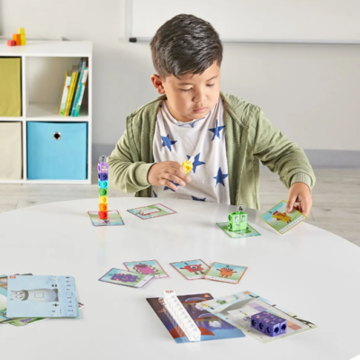 Criança a jogar com cartas e blocos coloridos numa mesa branca