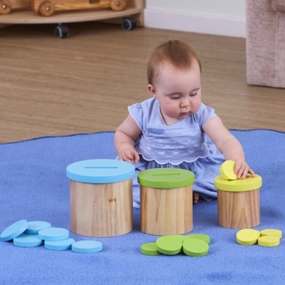 Bebé a brincar com brinquedos de madeira e tampas coloridas num tapete azul