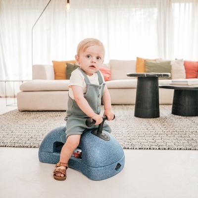 Criança sentada em brinquedo azul com rodas em sala de estar