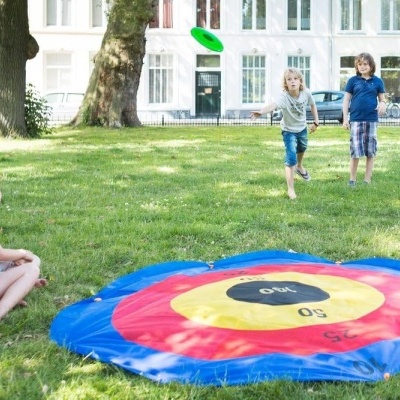 Tapete de jogo de dardos colorido na relva com crianças a jogar no parque