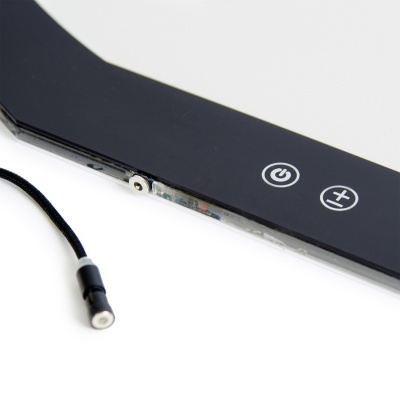 Dispositivo eletrônico preto com botões de ligar e aumentar, cabo preto ao lado