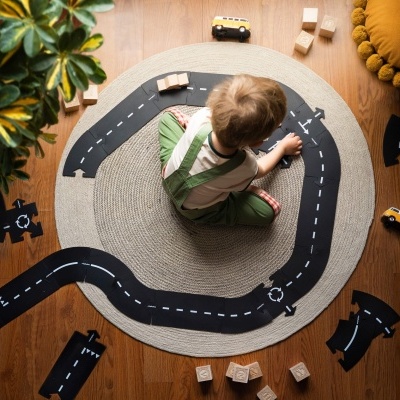 tapete redondo com estradas e brinquedos em madeira com criança