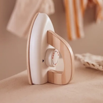 Ferro de engomar de brinquedo em madeira e branco numa superfície bege