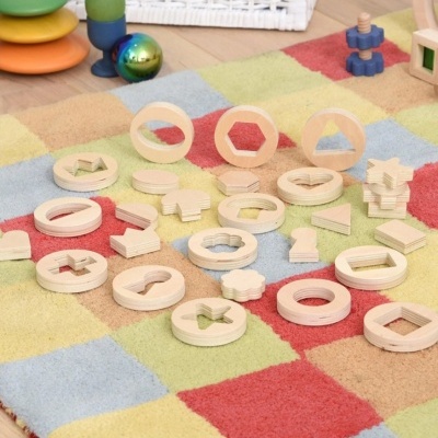 Brinquedos de madeira com formas geométricas sobre tapete quadriculado colorido