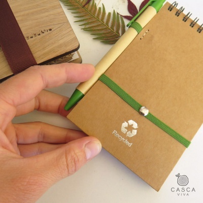 Caderno pequeno reciclado com suporte para caneta e caderno de madeira ao fundo