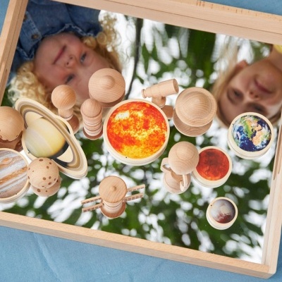 Brinquedos de madeira dos planetas do sistema solar sobre espelho numa caixa de madeira