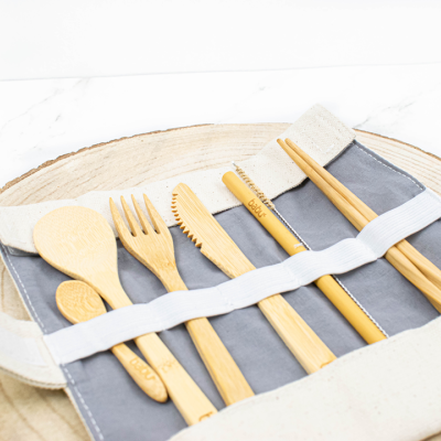 Conjunto de talheres de bambu numa bolsa cinza sobre fundo branco.