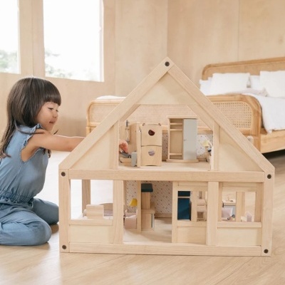 Casa de bonecas em madeira com vários quartos e móveis, com criança a brincar ao lado