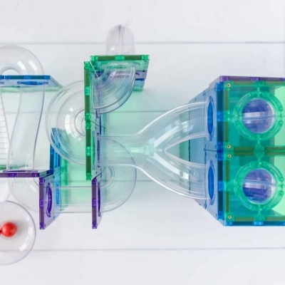 Estrutura modular de tubos transparentes coloridos com bolas vermelhas num tubo