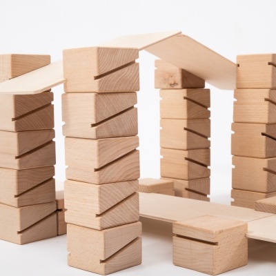 Blocos de madeira empilhados em colunas com telhados inclinados sobre base clara