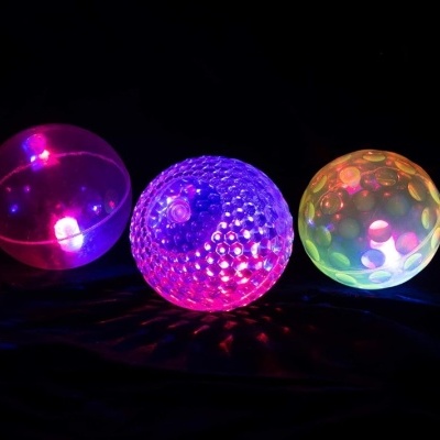 Três bolas transparentes iluminadas com LED em rosa, roxo e verde.