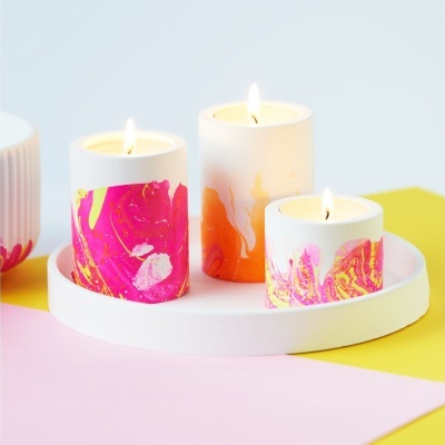 Três velas aromáticas coloridas acesas em bandeja branca