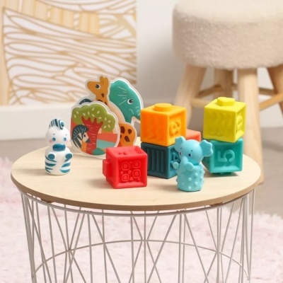 Brinquedos coloridos de animais e cubos empilhados sobre uma mesa redonda de madeira.
