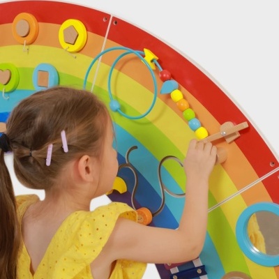 Menina a brincar com brinquedo educativo em arco-íris de madeira colorida