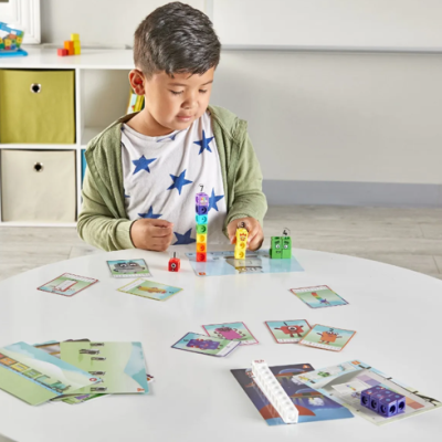 Menino a brincar com blocos numéricos e cartas numa mesa branca