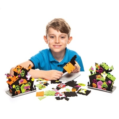 Casa de Halloween colorida feita de material de montar com decoração temática e menino sorridente ao fundo