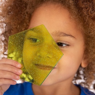 Criança segurando acrílico amarelo translúcido em forma de pentágono