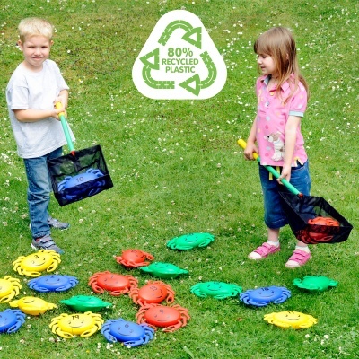 Crianças a brincar com pegadores no relvado e bolas coloridas, com símbolo de plástico reciclado