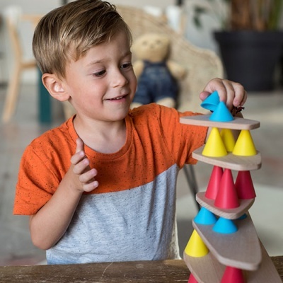 Criança a brincar com brinquedo de empilhar cones de madeira coloridos