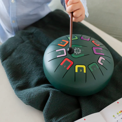 Tambor língua verde escuro colorido sobre tecido verde com mão segurando baqueta