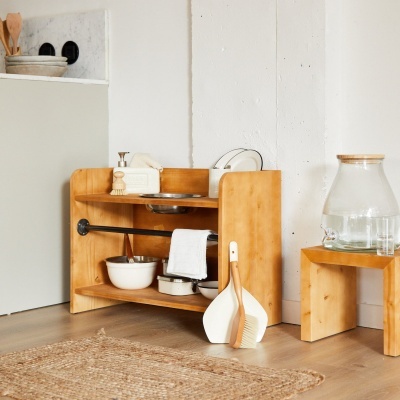 Estante de madeira com utensílios de cozinha e banco com jarra de vidro