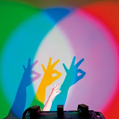 Sombra de mão fazendo gesto OK em projeção colorida