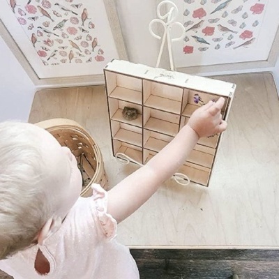 Bebé interagindo com calendário de advento de madeira com pequenas caixas numeradas