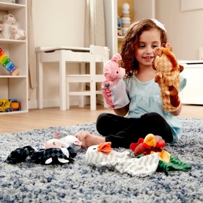 Criança brincando com marionetas de peluche numa sala infantil