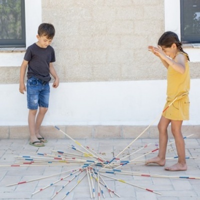 Crianças a jogar jogo de arremesso com varetas coloridas na área externa