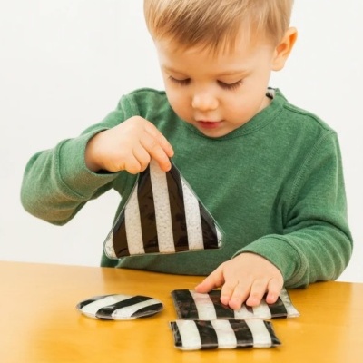 Criança a brincar com brinquedos geométricos preto e branco sobre mesa