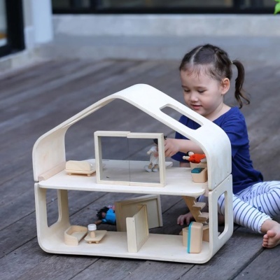 Casinha de brincar em madeira clara com dois andares e mobiliário pequeno