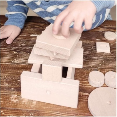 Criança a montar torre com blocos de madeira natural