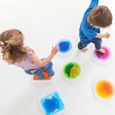 Crianças em almofadas sensoriais coloridas com líquidos