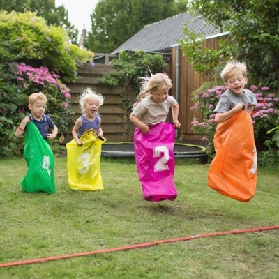 Crianças a saltar em sacos coloridos num jardim