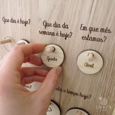 Quadro de madeira com discos rotativos para dias e meses, marcações em português.