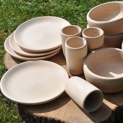 Utensílios de cozinha em madeira clara sobre tronco em relva