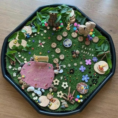 Jardim de fadas com relva artificial e decorações coloridas num suporte octogonal preto.